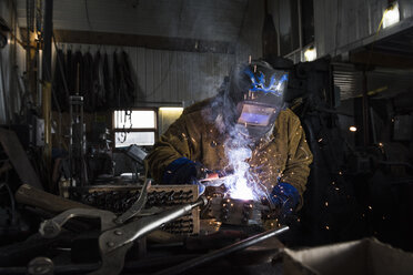 Schmied mit Schweißmaske beim Schweißen von Metall in der Werkstatt - CUF11071