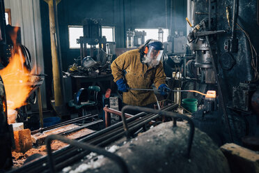 Schmied formt glühenden Metallstab in der Werkstatt - CUF11072