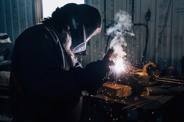 Schmied mit Schweißmaske beim Schweißen von Metall in der Werkstatt - CUF11077