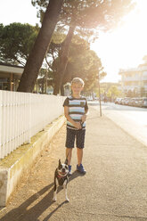 Portrait of boy with dog in street looking at camera smiling - CUF11080