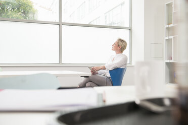 Woman in deep thought looking out of office window - CUF11097