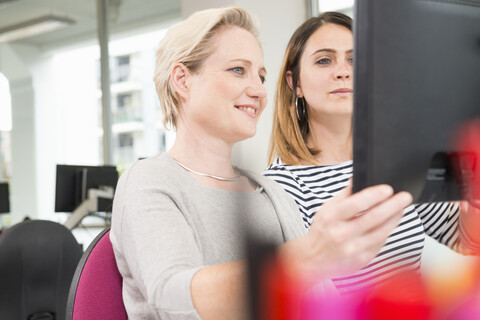Geschäftsfrauen im Gespräch am Laptop, lizenzfreies Stockfoto