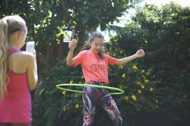 Mädchen fotografiert ihre Schwester beim Hoola Hooping im Garten - CUF11105