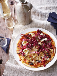 Pizza mit Schweinebauch, Chicorée und Balsamico auf weißem Teller, Blick von oben - CUF11125