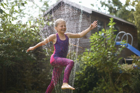 Mädchen springt über Garten-Sprinkler - CUF11160