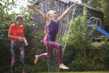 Mädchen springen über den Sprinkler im Garten - CUF11162