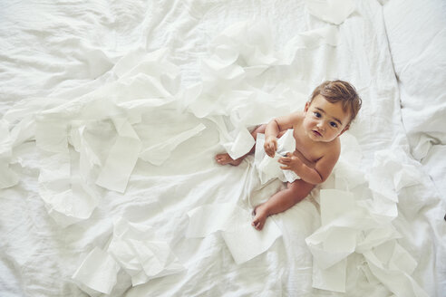 Kleinkind auf dem Bett sitzend, mit aufgerollter Toilettenpapierrolle - CUF11212