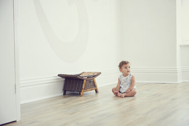 Toddler sitting on floor in bare room - CUF11216