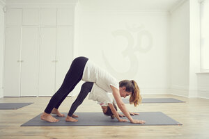 Mutter und Tochter im Yogastudio, zusammen in Yogaposition stehend - CUF11220