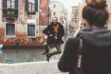 Frau fotografiert Mann, der durch den Kanal springt, Venedig, Italien - CUF11255