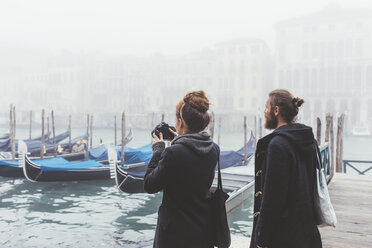 Paar fotografiert Gondeln auf nebligem Kanal, Venedig, Italien - CUF11260