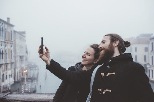 Paar macht Smartphone-Selfie über einem nebligen Kanal, Venedig, Italien - CUF11263