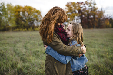 Mother and daughter hugging in meadow, Lakefield, Ontario, Canada - CUF11267