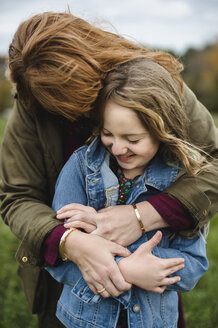 Mutter und Tochter umarmen sich auf einer Wiese - CUF11271