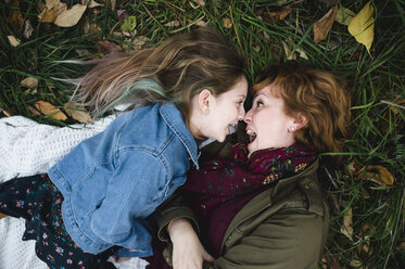 Mutter und Tochter liegen im Gras und machen lustige Gesichter - CUF11272