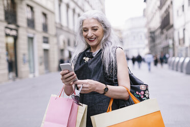 Elegante reife Frau, die auf der Straße ihr Smartphone betrachtet, Florenz, Italien - CUF11274