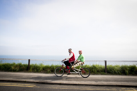 Quirky couple sightseeing on tandem bicycle, Bournemouth, England stock photo