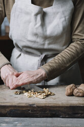 Woman chopping walnuts on chopping board, using knife, mid section - CUF11305