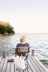 Frau sitzt auf Pier am Wasser - CUF11315