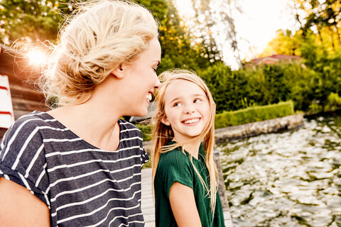 Mother and daughter enjoying themselves by water stock photo