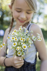 Girl pleased with bunch of camomile flowers - CUF11339