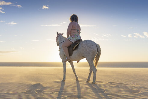 Woman riding horse on beach, rear view, Jericoacoara, Ceara, Brazil, South America - CUF11349