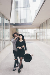 Junges Paar geht in städtischer Umgebung spazieren, albert herum, lacht - CUF11359