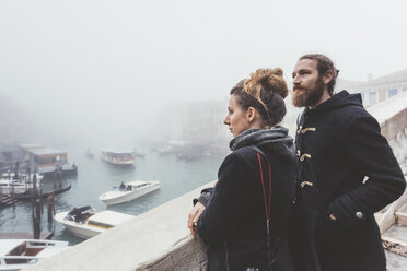 Couple looking out over misty canal, Venice, Italy - CUF11367