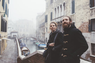 Couple leaning against misty canal bridge, Venice, Italy - CUF11370