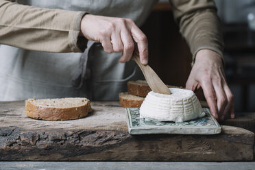 Frau schneidet ganzen Ricotta, Scheibe Brot auf Schneidebrett, Mittelteil - CUF11389