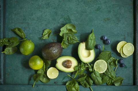 Spinach leaves, avocados and blueberries on green ground stock photo