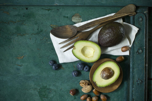 Tuch, Salatbesteck, Avocados, Blaubeeren und Nüsse auf grünem Grund - ASF06186