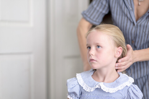 Mutter frisiert ihre kleine Tochter, lizenzfreies Stockfoto