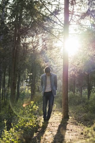 Young man standing in forest, against the sun stock photo