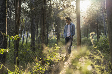 Junger Mann im Wald stehend, gegen die Sonne - AFVF00472