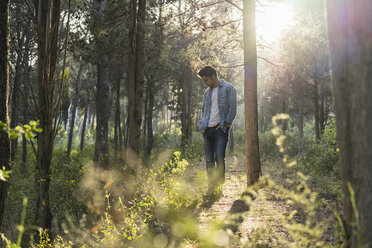 Junger Mann im Wald stehend, gegen die Sonne - AFVF00473