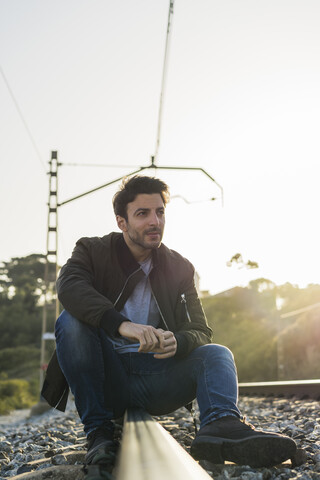 Young man sitting on railroad track stock photo