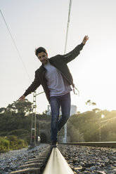 Young man standing on railroad track - AFVF00479