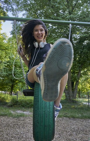 Portrait of happy young woman on a swing stock photo