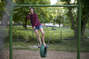 Laughing young woman having fun on a swing - BEF00091