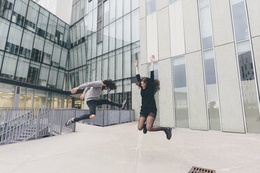 Young couple in urban environment, jumping for joy - CUF11428