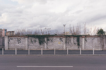 Graffiti on wall beside deserted road - CUF11434