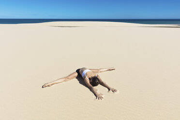 Frau am Strand in Yogaposition, nach vorne gebeugt im Spagat - CUF11440