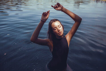Porträt einer Frau im Badeanzug, im Wasser stehend, Arme erhoben, Augen geschlossen - CUF11450