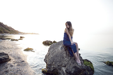 Junge Frau sitzt auf einem Felsen am Strand, Odessa, Ukraine - CUF11475