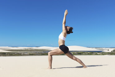 Seitenansicht einer Frau am Strand mit erhobenen Armen, die sich in Yoga-Position strecken - CUF11525