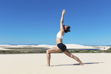 Side view of woman on beach arms raised stretching in yoga position - CUF11525