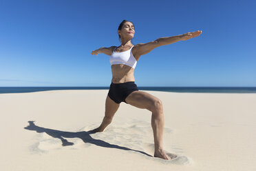 Woman on beach arms open stretching in yoga position - CUF11527