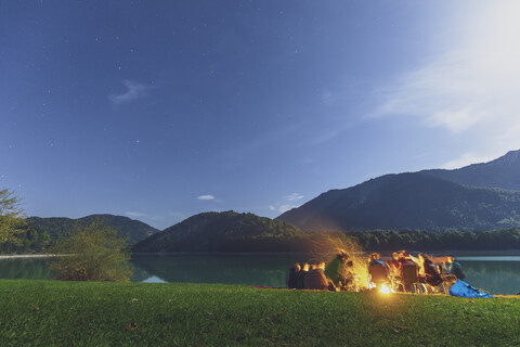 Deutschland, Bayern, Talsperre Sylvenstein, Gruppe von Menschen am Lagerfeuer in der Nacht, lizenzfreies Stockfoto