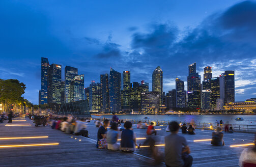 Tourists looking at city skyline from waterfront at dusk, Singapore, South East Asia - CUF11608